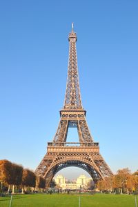 Eiffel tower over field against clear blue sky