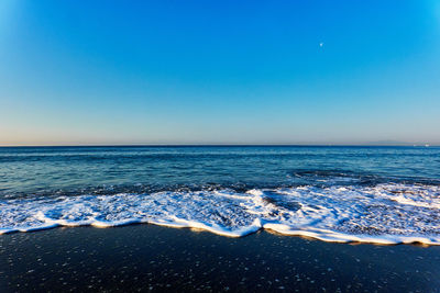 Scenic view of sea against clear blue sky during sunrise