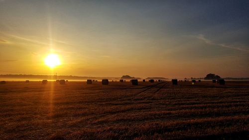 Hay bales on field against sky during sunset