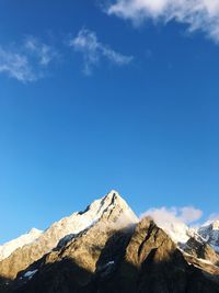 Low angle view of snowcapped mountains against blue sky