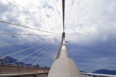 Low angle view of suspension bridge against cloudy sky