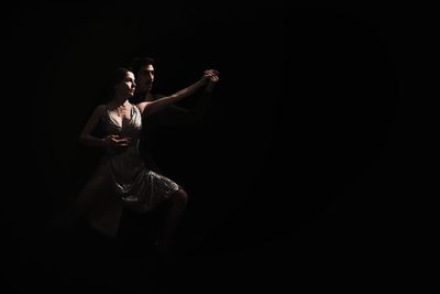 Midsection of woman standing against black background