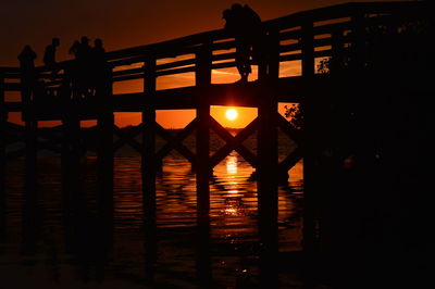 Silhouette people in water at sunset