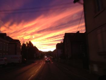 Road passing through city at sunset