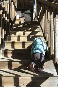 Rear view of girl crawling on staircase
