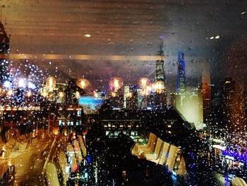 Illuminated cityscape seen through window at night