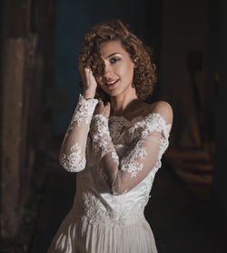 Portrait of sensuous young woman in wedding dress standing at home