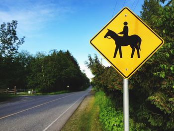 Road sign by street against sky