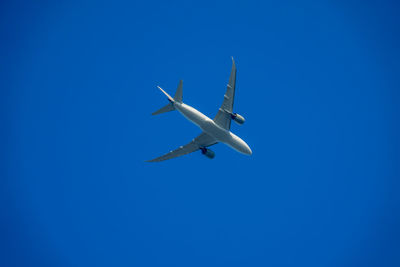 Low angle view of airplane against clear blue sky