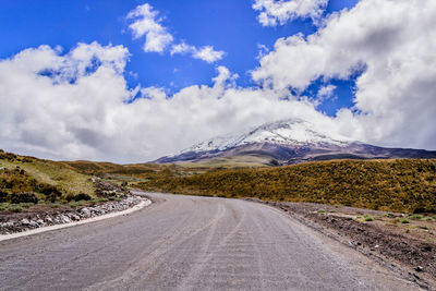 Road leading towards mountains against sky