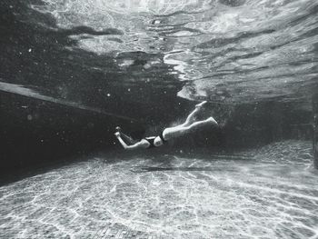 Low section of man jumping in swimming pool