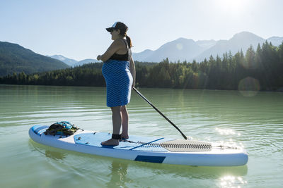 Pregnant female riding sup board on mountain lake