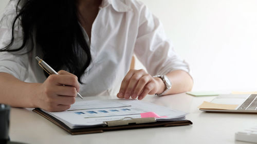 Midsection of woman using laptop on table