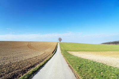 Road amidst field against sky