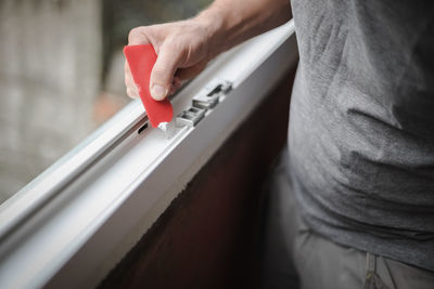 A young man covers up a hole in the window frame with a spatula.