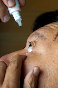 Close-up of mature man inserting eye drop