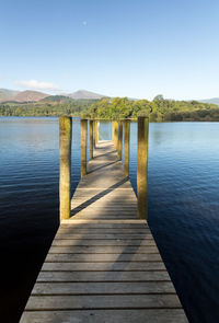 Wooden pier on lake against clear sky