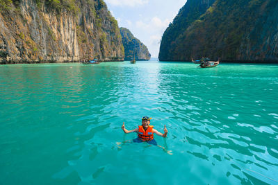 Portrait of smiling man wearing life jacket gesturing in sea