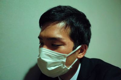 Close-up of young man wearing mask against wall