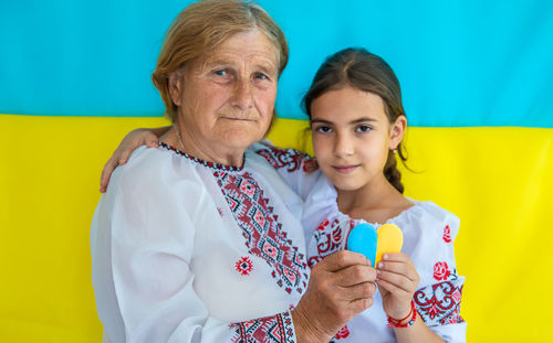 Smiling senior woman with girl holding heart shape candy