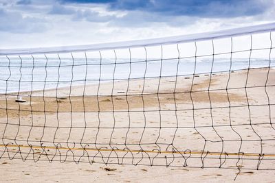 Volleyball net at beach against sky