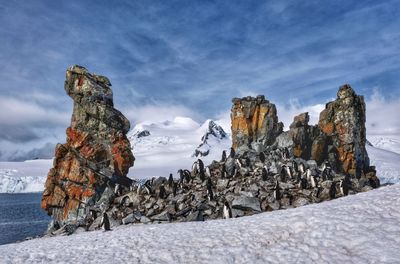 Rocks on snow covered land against sky