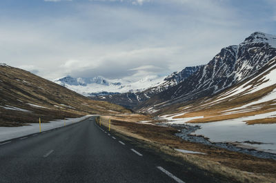 Road amidst snowcapped mountains against sky