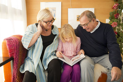 Grandparents reading book with granddaughter