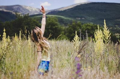 Rear view of woman walking on field by mountain