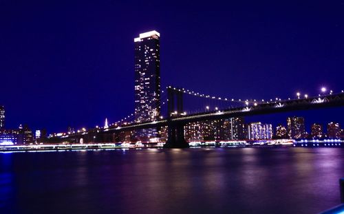 Illuminated bridge over river at night