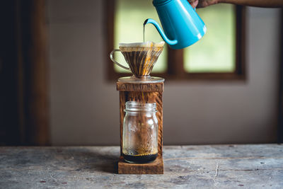 Black coffee pouring in jar on table
