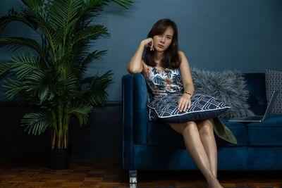 Young woman looking away while sitting on chair