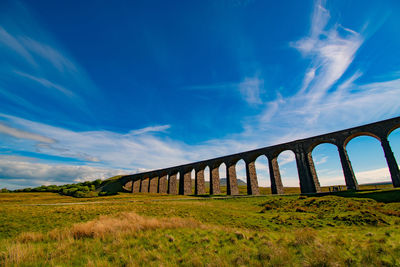 Arch bridge on field against sky