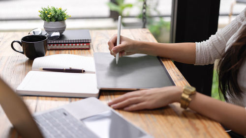 Female hands working with digital tablet, laptop and stationery on the desk in workplace