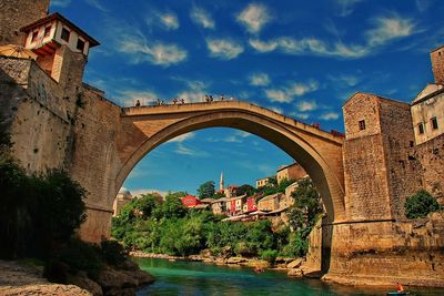 Arch bridge over river against sky