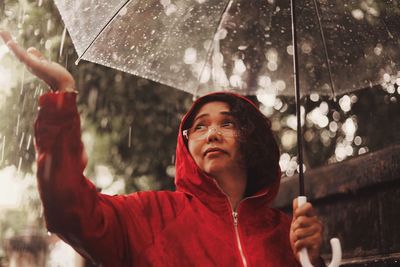 Portrait of man holding wet umbrella during rainy season