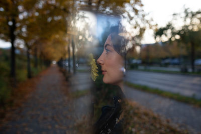 Portrait of young woman standing by tree