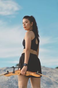 Portrait of young woman standing against sky