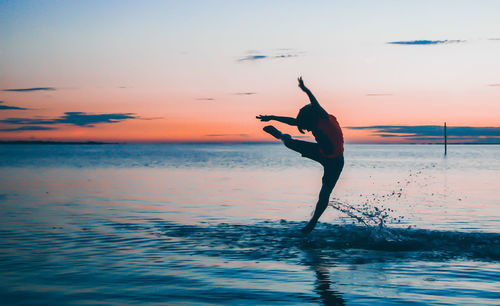 Boy jumping at sea during sunset