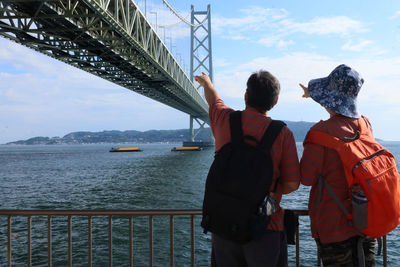 Rear view of men on bridge against sky