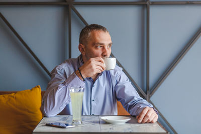 Businessman drinking coffee while sitting in cafe