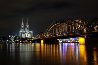 Illuminated bridge over river at night