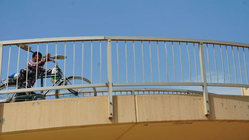 People on bridge against clear blue sky