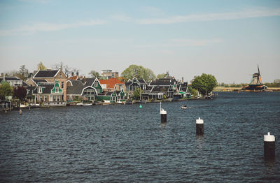 Houses by lake against sky