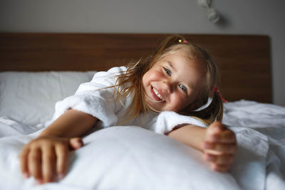 Portrait of smiling girl lying on bed at home