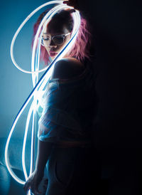 Midsection of woman with light painting against black background