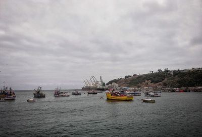 Boats in sea against cloudy sky