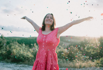 Smiling woman with arms outstretched standing outdoors