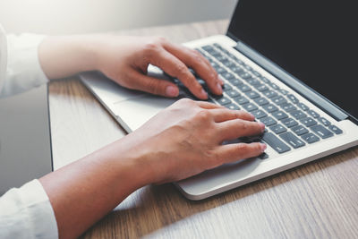 Midsection of woman using laptop on table