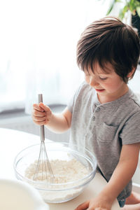 Adorable cheerful boy, toddler kneads dough in the kitchen. children cat dough at home. 